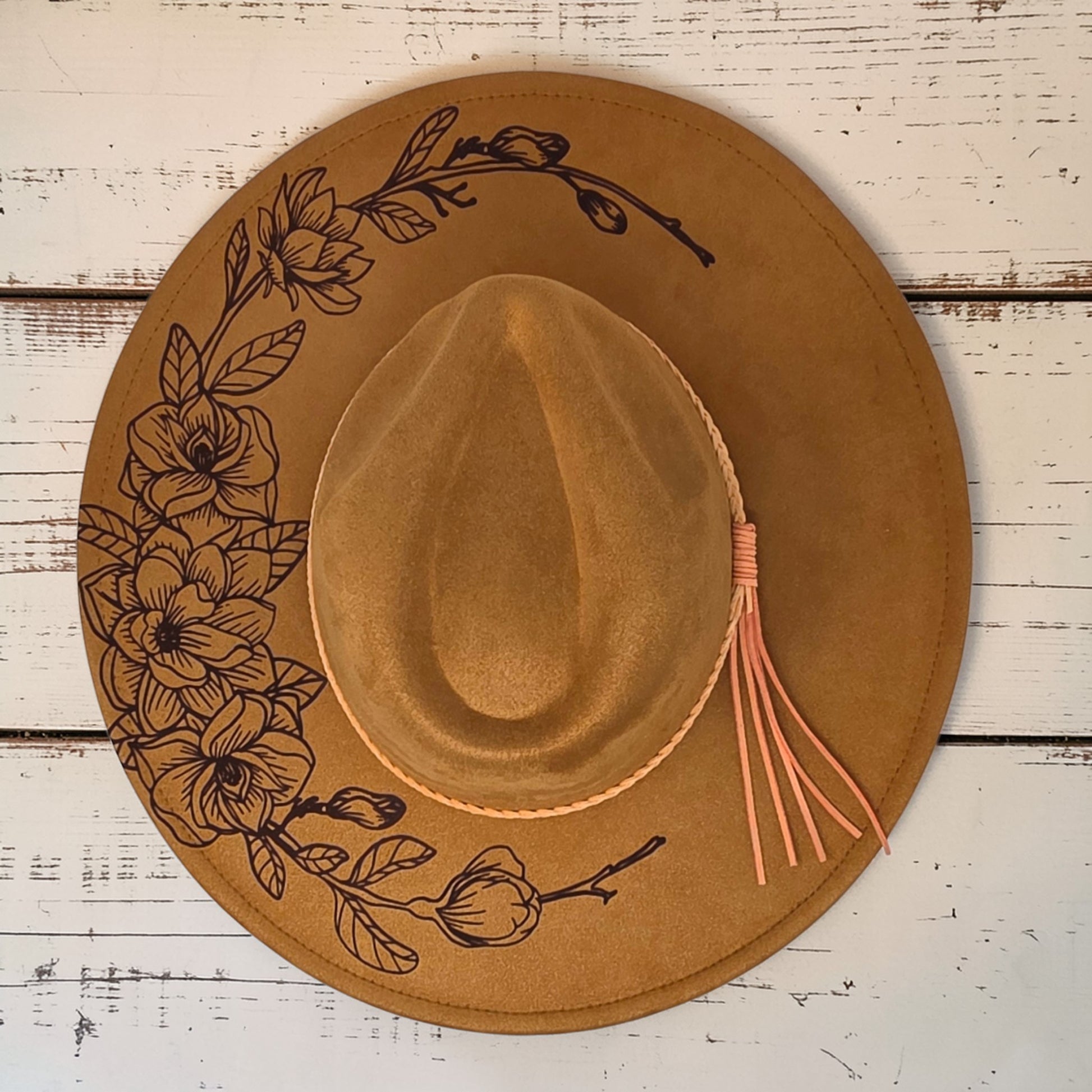 Elkhorn Designs chestnut vegan suede wide-brim hat with laser-engraved gardenia floral design and braided tassel band.