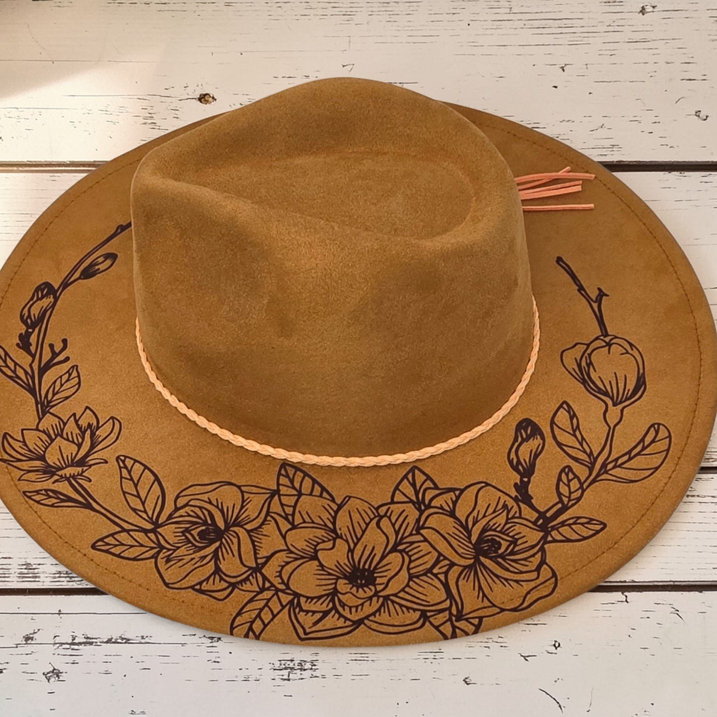 Elkhorn Designs chestnut vegan suede wide-brim hat with intricate laser-engraved gardenia floral design and tassel.