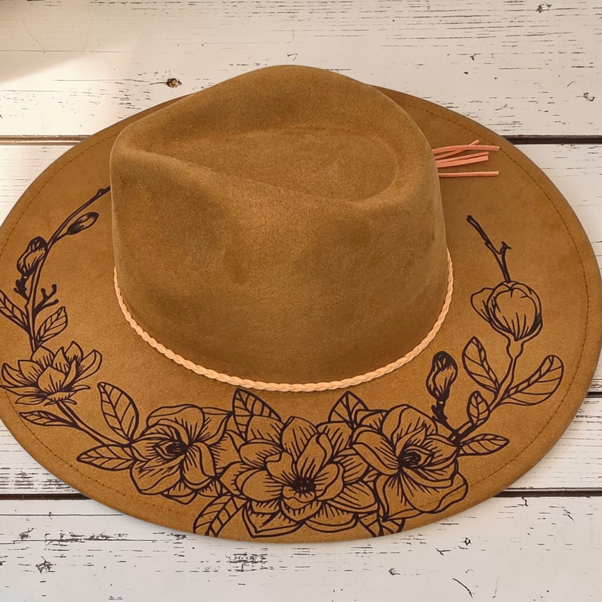 Elkhorn Designs chestnut vegan suede wide-brim hat with intricate laser-engraved gardenia floral design and tassel.
