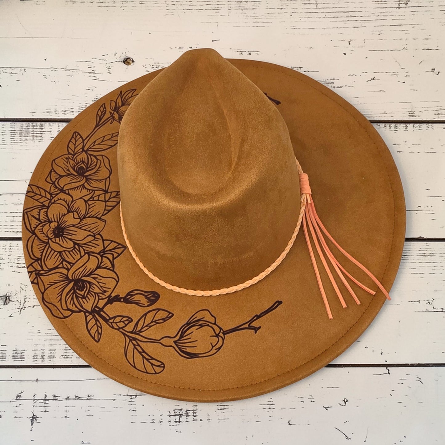 Elkhorn Designs chestnut vegan suede wide-brim hat with laser-engraved gardenia floral design and braided tassel band.