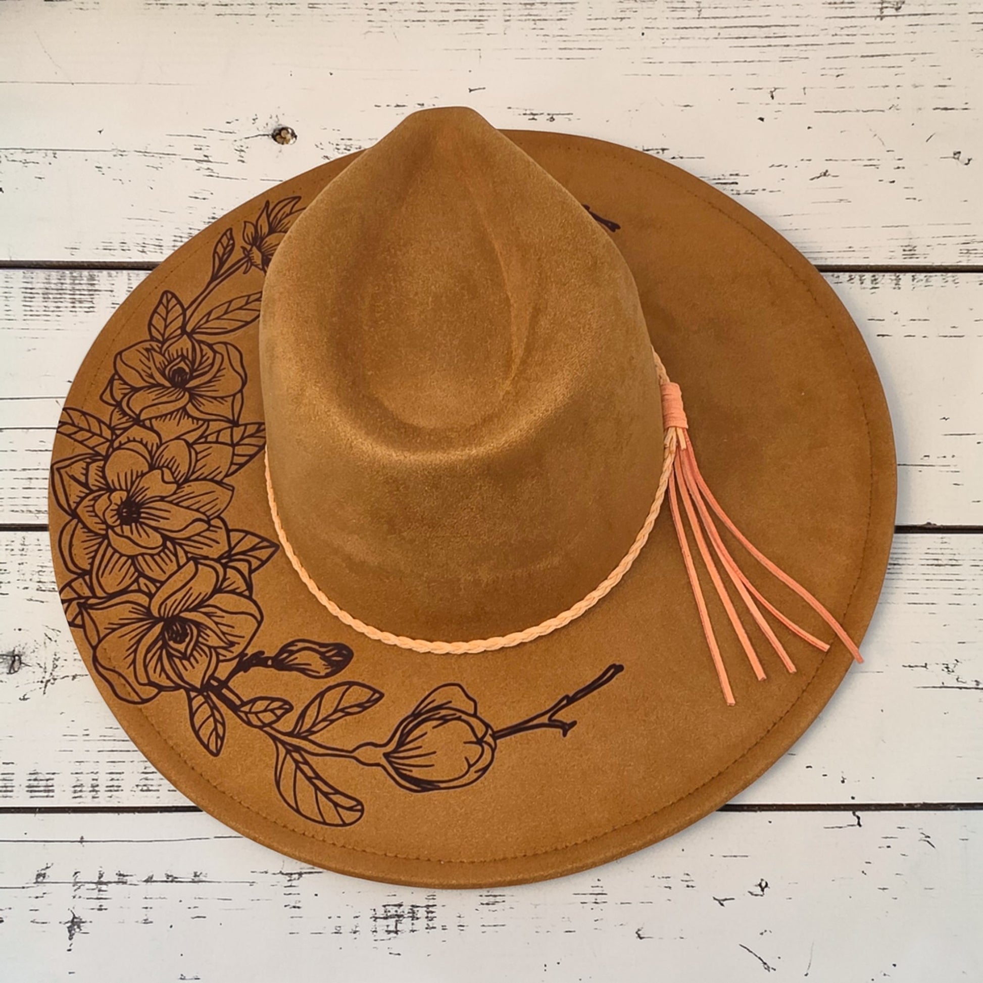 Elkhorn Designs chestnut vegan suede wide-brim hat with laser-engraved gardenia floral design and braided tassel band.