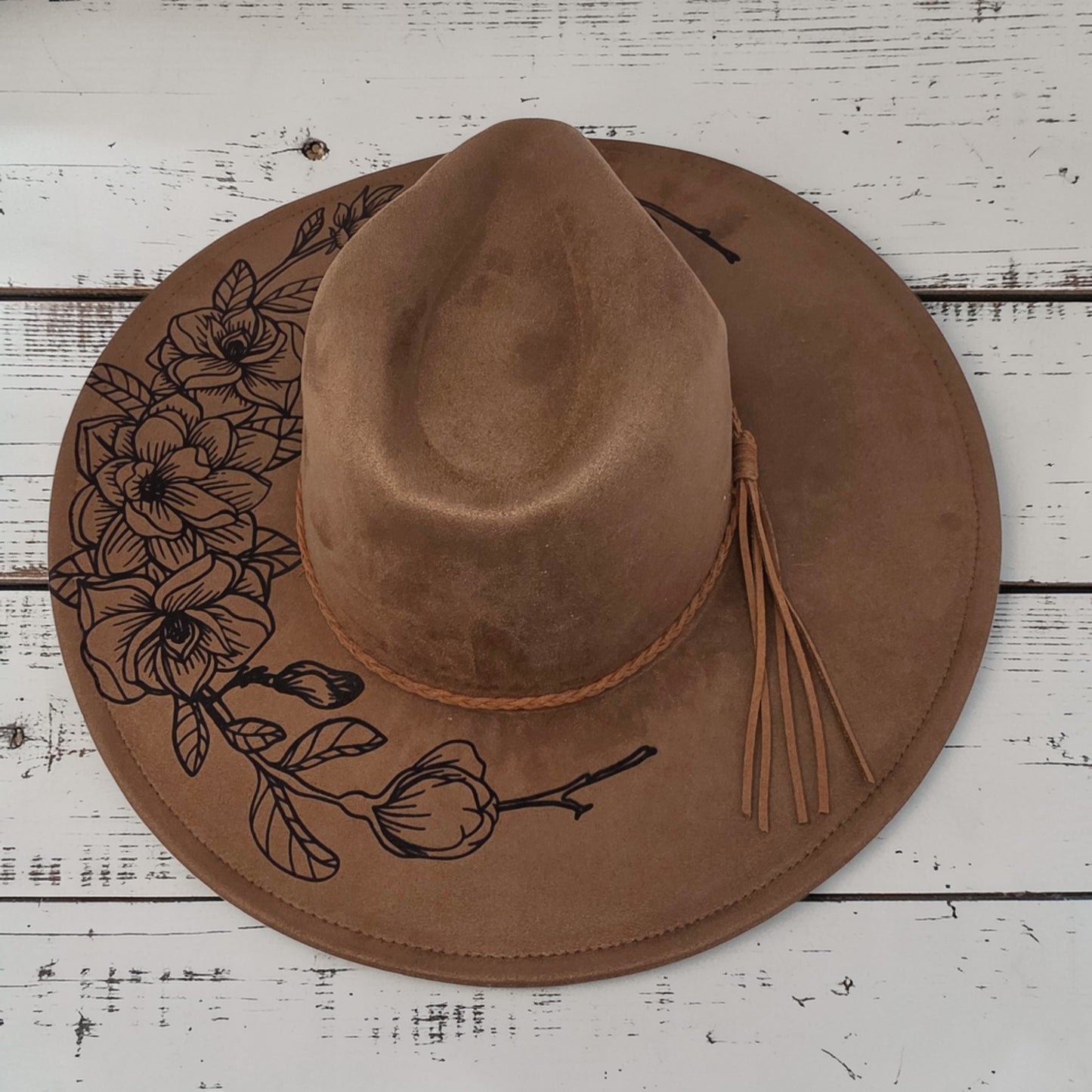 Elkhorn Designs chestnut vegan suede wide-brim hat with laser-engraved gardenia floral design and braided tassel band.