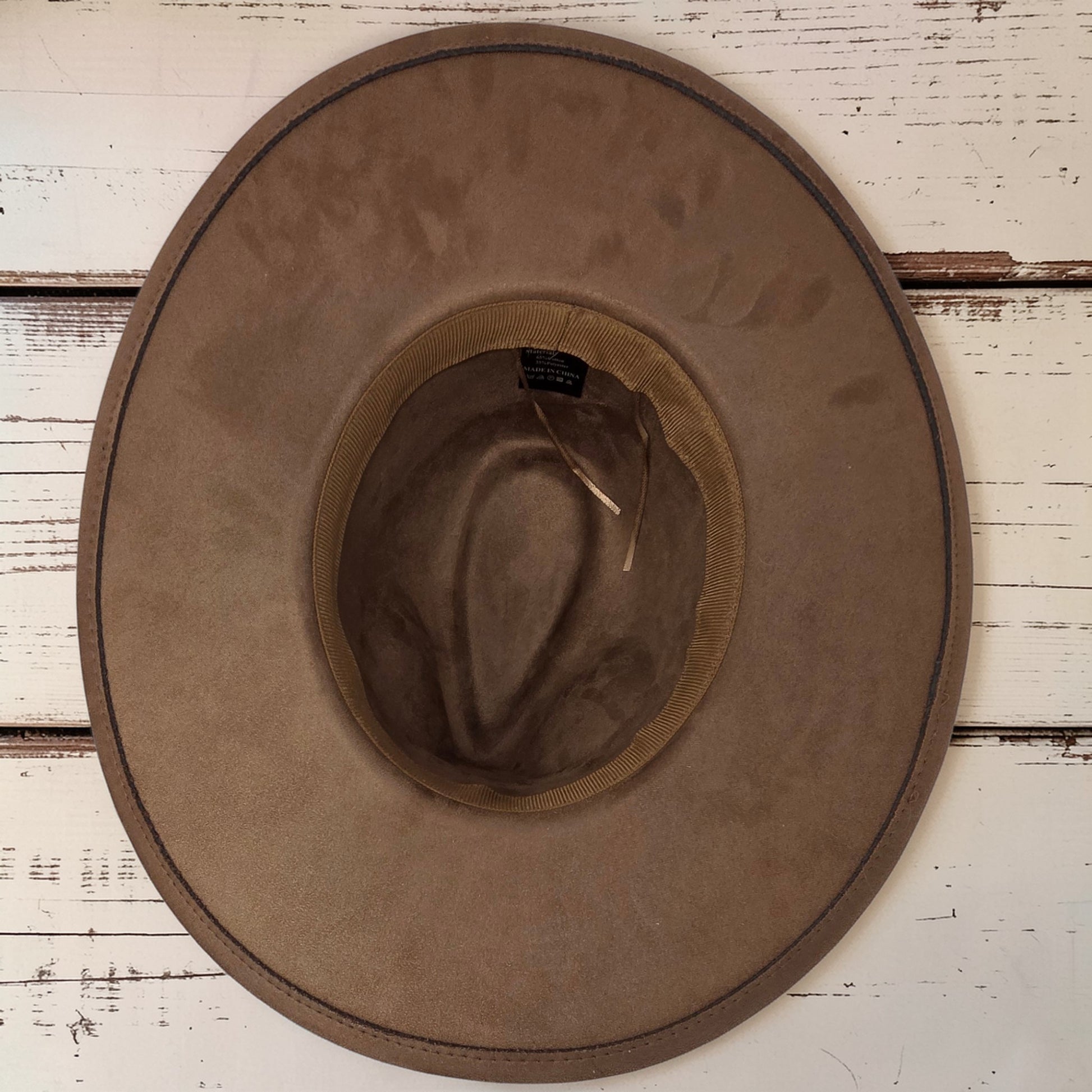Elkhorn Designs chestnut vegan suede wide brim hat with interior view on a rustic white wooden background