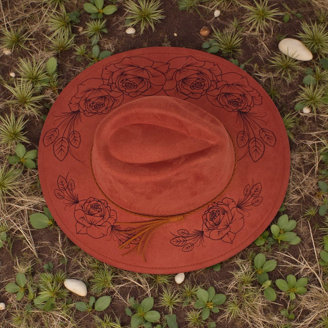 Elkhorn Designs rust-colored vegan suede wide-brim hat with intricate laser-engraved floral patterns on the brim.
